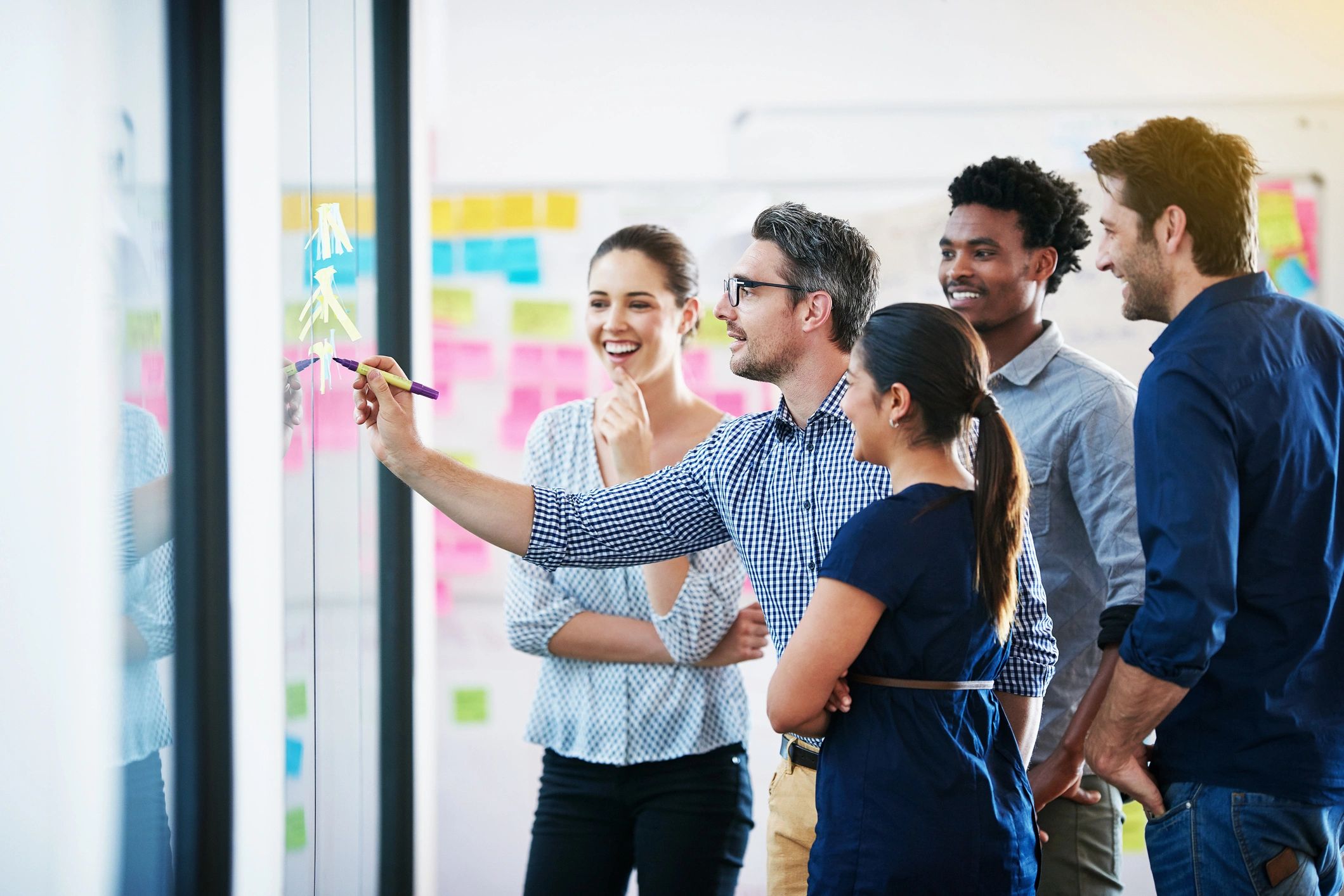 Marketing team brainstorming campaign ideas on a glass wall